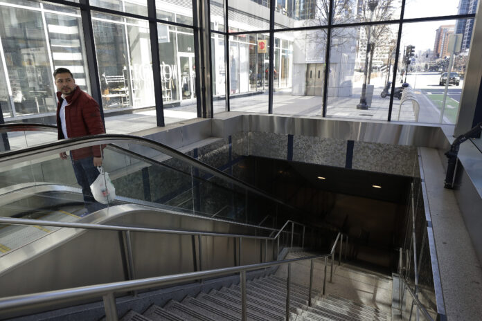CHARLIE BAKER has asked all visitors to the state to self-quarantine for 14 days. The Massachusetts tax deadline has also been delayed to July 15. Above, a man exits a subway station in the Seaport District, in BostonMany people are working from home while many businesses have closed indefinitely because of the coronavirus, leaving portions of the city nearly empty. AP FILE PHOTO/ STEVEN SENNE