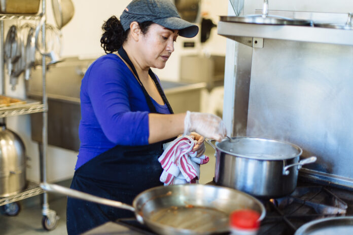 CHEF ROSA Muñoz, who works for Hope & Main member entity Savory Fare, prepares a meal in one of Hope & Main's kitchens. Hope & Main is launching next week its new Nourishing Our Neighbors program to provide free meals to seniors and needy families on the East Bay during the COVID-19 pandemic. / COURTESY RUPERT WHITELEY CHEF ROSA Muñoz, who works for Hope & Main member entity Savory Fare, prepares a meal in one of Hope & Main's kitchens. Hope & Main is launching next week its new Nourishing Our Neighbors program to provide free meals to seniors and needy families on the East Bay during the COVID-19 pandemic. / COURTESY RUPERT WHITELEY