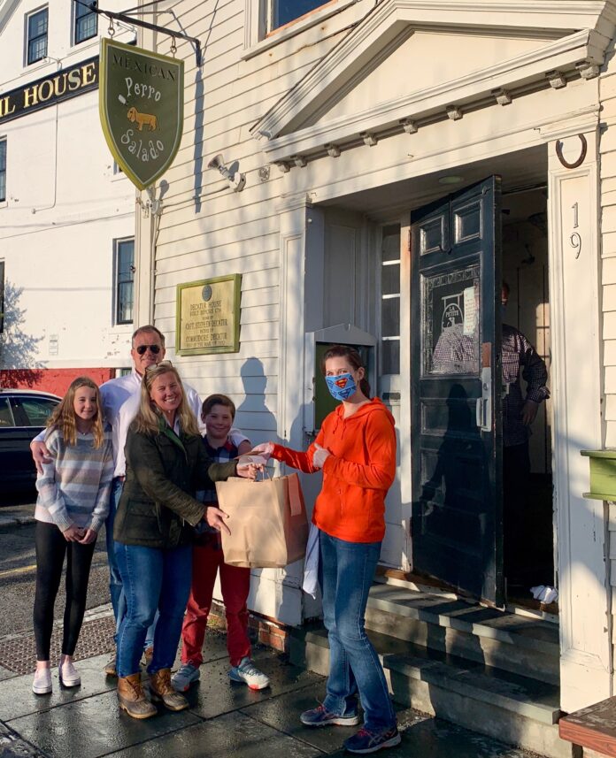 HOGAN ASSOCIATES realtor Caroline Richards, center, picks up a dinner and gift cards from Perro Salado in Newport as part of the agency's 1 MORE HELPING initiative to offer assistance to the community impacted by the COVID-19 pandemic. / COURTESY HOGAN ASSOCIATES HOGAN ASSOCIATES realtor Caroline Richards, center, picks up a dinner and gift cards from Perro Salado in Newport as part of the agency's 1 MORE HELPING initiative to offer assistance to the community impacted by the COVID-19 pandemic. / COURTESY HOGAN ASSOCIATES