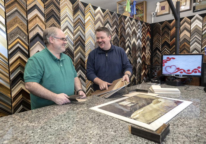 ENDLESS CHOICES: Customers can choose from up to 4,000 styles and an array of finishes at Get The Picture, a custom framing shop in Lincoln launched nearly 20 years ago by owners Andy Langlois, right, and Mike Labbe. / PBN PHOTO/MICHAEL SALERNO ENDLESS CHOICES: Customers can choose from up to 4,000 styles and an array of finishes at Get The Picture, a custom framing shop in Lincoln launched nearly 20 years ago by owners Andy Langlois, right, and Mike Labbe. / PBN PHOTO/MICHAEL SALERNO