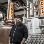 STILL PRODUCING: Dan Neff is a co-owner of The Industrious Spirit Co. in Providence. The distillery was prepared to open a tasting room for the public before the new coronavirus hit. Industrious Spirit is still selling its Structural Vodka through a walk-up window at the distillery. / PBN PHOTO/MICHAEL SALERNO
