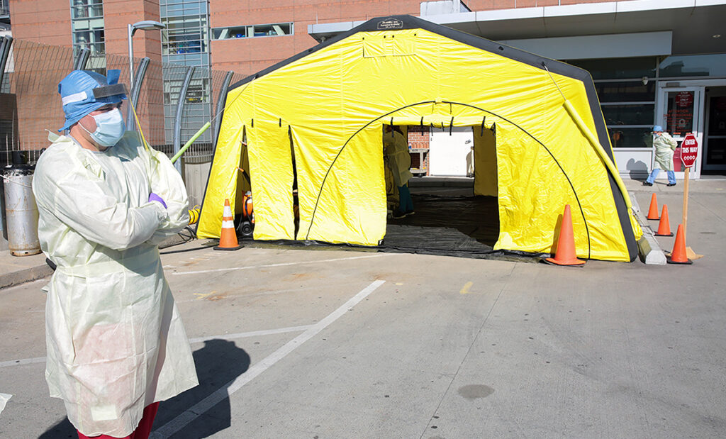AWAITING PATIENTS: An R.I. Department of Health worker waits outside the incoming COVID-19 patient tent set up outside Rhode Island Hospital in Providence. The tent is used by health department workers to administer coronavirus tests for people who have been approved by state health officials to receive them. / COURTESY LIFESPAN CORP.