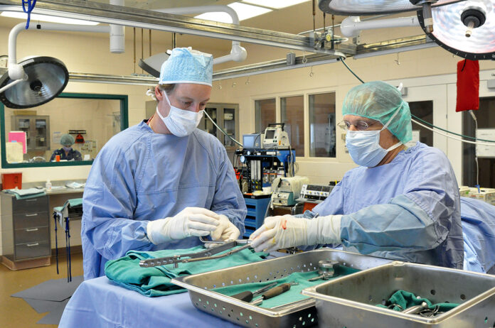 TECH IN USE: John Jarrell, left, president of Materials Science Associates, and Dr. Christopher Born, director of orthopedic trauma at Rhode Island Hospital, work to apply a patented anti-microbial technology in a surgical procedure to reduce infection of medical implants. ­Jarrell has increased his company’s investment in patent filings and other intellectual property activity to respond to ­COVID-19. / COURTESY MATERIALS SCIENCE ASSOCIATES LLC
