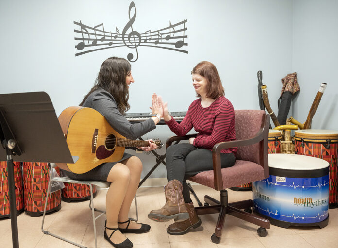 DUAL HARMONY: Nicole O’Malley, left, is the founder and executive director of Hands in Harmony, which uses musical therapy to help individuals with complex medical conditions. Here, O’Malley works with longtime client Abigail Magiera, 21, of Coventry. / PBN PHOTO/DAVE HANSEN