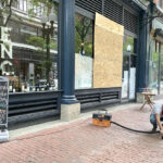 MOVING ­FORWARD: Domenic Merolla, a clerk at ENO Fine Wines in Providence, on June 2 cleans up shattered glass and spilled alcohol from looting at the store. / PBN PHOTO/  NANCY LAVIN