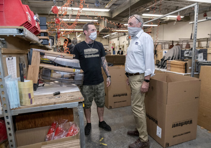 TESTED: WaterRower Inc. CEO and President Peter King, right, speaks with assembly worker Lenny Laur. The Warren manufacturer has managed two COVID-19 outbreaks among employees. / PBN FILE PHOTO/MICHAEL SALERNO