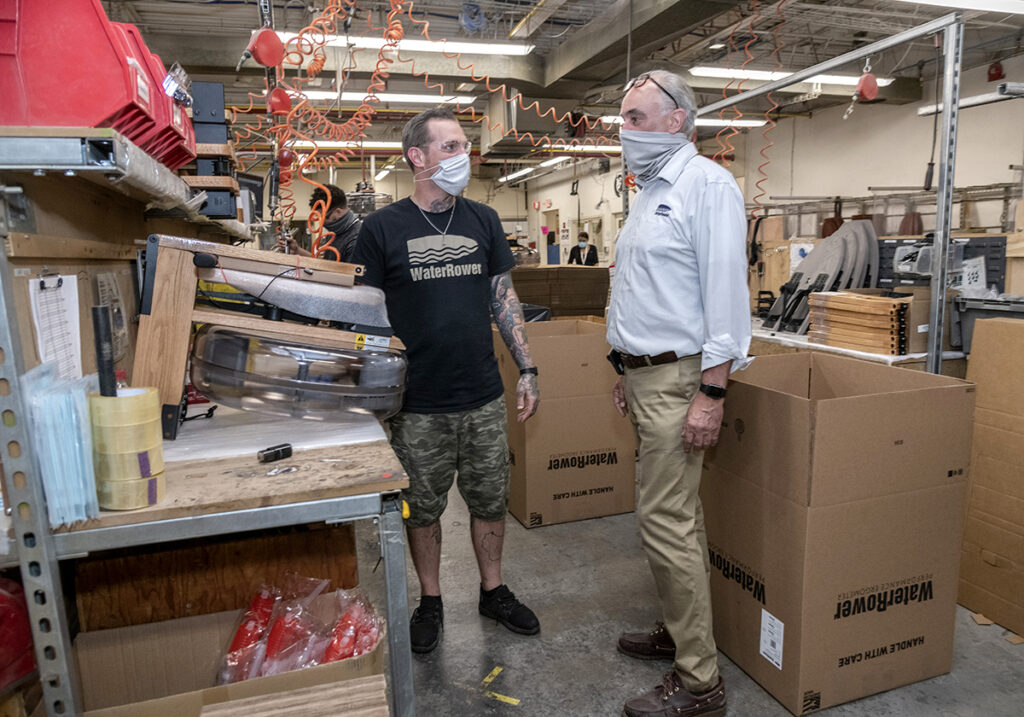 PROTECTIVE MODE: WaterRower Inc. CEO and President Peter King, right, speaks with assembly worker Lenny Laur. After a COVID-19 outbreak at the Warren factory, King says, he wanted to test the entire company of 200 employees for the virus but was advised against it by state officials. / PBN PHOTO/MICHAEL SALERNO