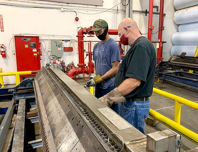 COLLABORATORS: Terry Thompson, left, extruder setup, and Mike Funderburk, master mechanic, team up to perform predictive maintenance on an extruder die at Cooley Group’s Pawtucket facility. / COURTESY COOLEY GROUP COLLABORATORS: Terry Thompson, left, extruder setup, and Mike Funderburk, master mechanic, team up to perform predictive maintenance on an extruder die at Cooley Group’s Pawtucket facility. / COURTESY COOLEY GROUP