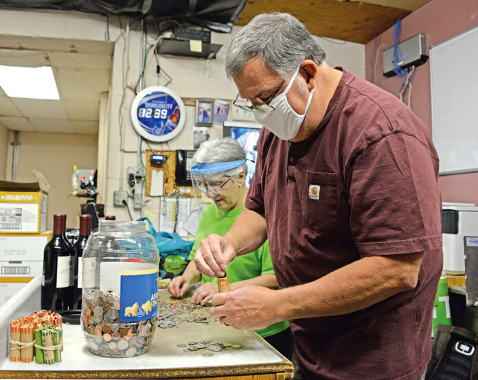 ROLLING WITH THE PUNCHES: Richard “Rippy” Serra, owner of Rippy’s Liquor and Marketplace in Charlestown, and office manager Donna McAdams roll coins brought in by customers. In an effort to combat the national coin shortage, Serra offers free coin rolling to customers to exchange their coins for dollar bills. / PBN PHOTO/ELIZABETH GRAHAM