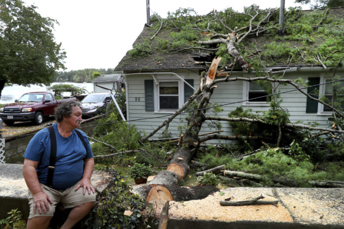 DAVID HAIGH looks at a large tree that fell on his home on in Pembroke, Mass on Wednesday, Sept. 30, 2020 after a storm passed the area. The National Weather Service reported that winds gusted as high as 72 mph near Boston at around 7 a.m. Wednesday before leveling off through the morning. / AP FILE PHOTO/JOHNVTLUMACKI/THE BOSTON GLOBE