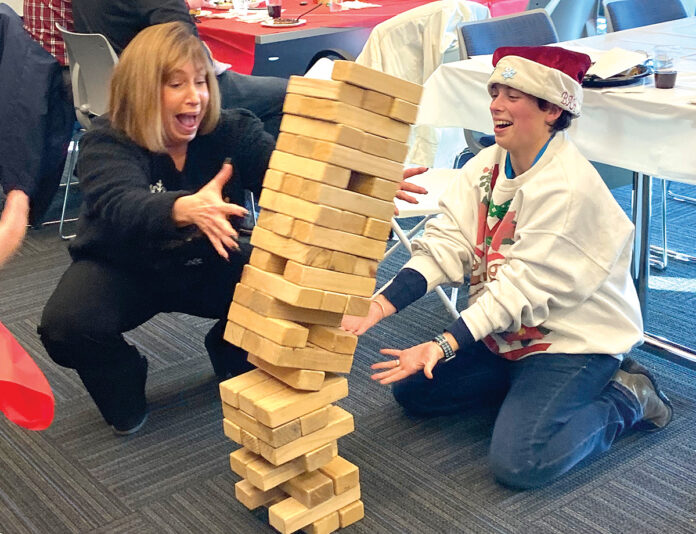 GAME DAY: Narragansett Bay Commission Executive Director Laurie Horridge, left, and Liz Kohr enjoy a game of Jenga at a holiday employee appreciation event. / COURTESY NARRAGANSETT BAY COMMISSION