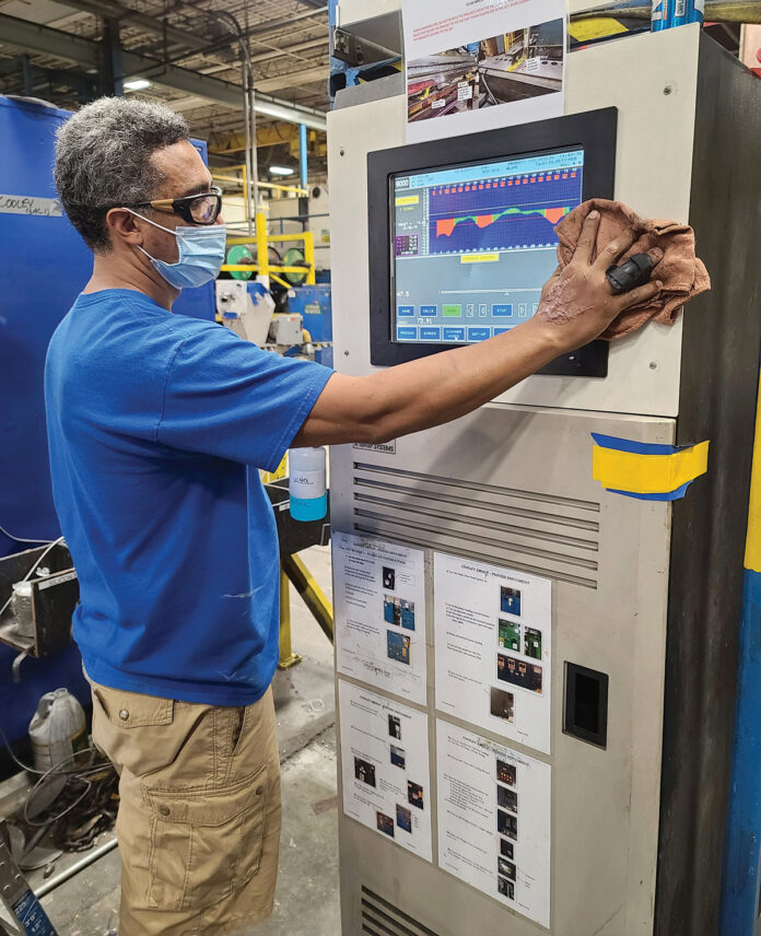 MR. CLEAN: Ben Pereira, extruder team leader, disinfects his extrusion touch screen at Cooley Group’s Pawtucket factory. / COURTESY COOLEY GROUP