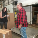 ALL-IN: Christine Soave Crum, left, owner of Gentry Moving and Storage in Cranston, accepts a delivery of office furniture from Don Erickson of Aspen Transport Service. Crum worked full time as a teacher when she founded the moving company with a partner in 2005 but now focuses all of her attention on Gentry. / PBN PHOTO/MICHAEL SALERNO