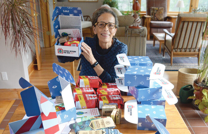 MEANINGFUL GIFTS: Giving Beyond the Box owner Sandra Enos assembles a themed gift box with items from social enterprises. / PBN PHOTO/ELIZABETH GRAHAM