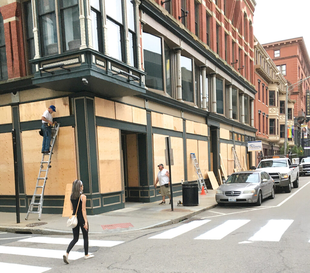 PREPPING FOR THE WORST: Workers install plywood over the windows of the Rhode Island Housing offices on Washington Street in Providence on June 4, 2020, just days after protests over George Floyd’s death devolved into looting. At the time, property owners and businesses feared more damage. / PBN PHOTO/WILLIAM HAMILTON