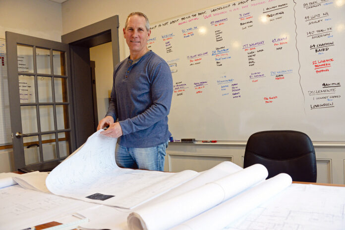 PAPER TRAIL: Jeff Sweenor, founder, CEO and president of Sweenor Builders Inc., used to meet with all of his clients face to face to review paper blueprints of projects. Now most of the designs are reviewed in videoconferences. / PBN PHOTO/ELIZABETH GRAHAM