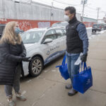 LOADING UP: Meg Grady, executive director for Meals on Wheels of Rhode Island, and volunteer Ted Fischer, CEO of Ageless Innovation, help load food into vehicles for some deliveries. Grady said the organization’s home-delivery program saw a 7% increase in seniors served and a 9% increase in meals served in 2020 compared with 2019. / PBN PHOTO/MICHAEL SALERNO
