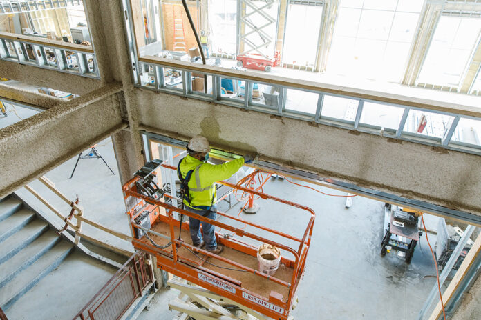 UNFINISHED: A Gilbane Inc. worker inspects a beam at the East Providence High School construction project the company has undertaken. At four stories and 300,000 square feet in size, the $190 million building is the largest K-12 project in state history. / PBN PHOTO/RUPERT WHITELEY 
