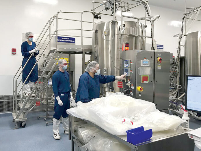 CLOSE EYE: From left, associate manufacturer Adeline Lamothe, manufacturing process technician contract worker Austin White and associate manufacturer David Folco check the single-use bioreactors, which are used to control the conditions for generating protein cells at Amgen Rhode Island in West Greenwich. / COURTESY AMGEN INC. 