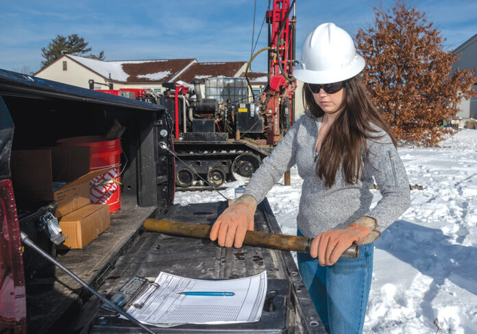 HANDS ON: Stephanie Robat, owner of FR Engineering Group Inc., prepares to examine a core sample brought up by a drill rig on a work site in ­Warwick. / PBN PHOTO/MICHAEL SALERNO