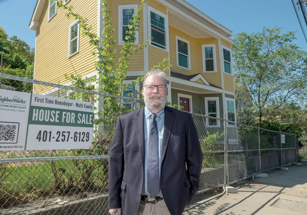 CREATING OPTIONS: ­Joseph Garlick, Neighbor­Works Blackstone River Valley executive director, stands in front of a renovated duplex in Woonsocket that will be sold to a moderate-income family. About two dozen people are vying to buy it for $169,000. / PBN PHOTO/MICHAEL SALERNO