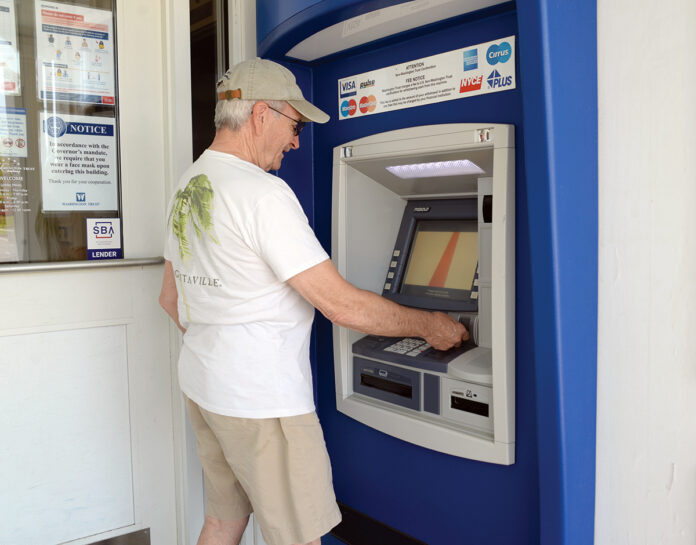 CASH FLOW: Russell Morrill of Westerly uses an ATM at The Washington Trust Co. branch in Westerly recently. Banks and credit unions are expecting to see a decline in the size of deposits as the COVID-19 crisis passes. / PBN PHOTO/ELIZABETH GRAHAM