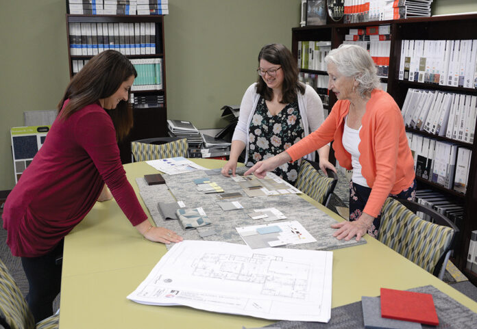 DESIGNING WOMEN: Phyllis Cannava, right, president of Office Direct Cannava Design Ltd., a commercial furniture dealership in Warwick, looks over samples and blueprints with senior designer Meghan Robinson, left, and designer Meghan Ryan. / PBN PHOTO/ELIZABETH GRAHAM