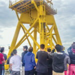 FUTURE WORKFORCE? Rhode Island high school students participating in a career pathway program for offshore wind jobs ride in a boat circling a Block Island Wind Farm turbine. / COURTESY DOUG LEARNED/LUCKY DAWG PHOTOGRAPHY