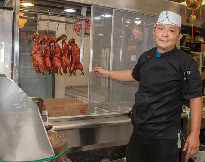 SIGNATURE OFFERING: Yewchanang Tan, owner of the New Wing Kee Barbeque & Poultry restaurant, located at 39 Central St. in Providence, hangs some of the fully cooked ducks for display. / PBN PHOTO/MICHAEL SALERNO