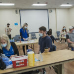 UNIVERSITY OF RHODE ISLAND students await getting their COVID-19 vaccines at a recent clinic. While students at all 11 Rhode Island-based colleges are required to get vaccinated before the fall, URI is among six colleges in the Ocean State not requiring faculty and staff to get vaccinated. / COURTESY UNIVERSITY OF RHODE ISLAND