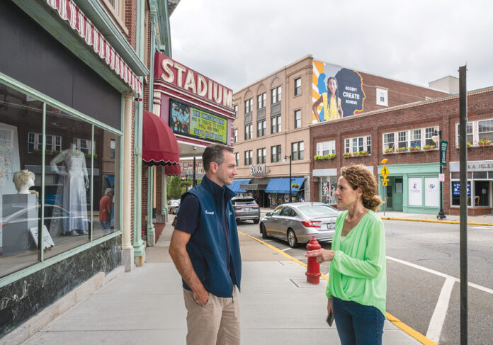 STILL STANDING: Downtowns across the state are hoping to fuel a post-pandemic rebound. Above, Woonsocket Mayor Lisa Baldelli-Hunt and Garrett Mancieri, director of the Downtown Woonsocket Collaborative, in Monument Square. / PBN FILE PHOTO/ MICHAEL SALERNO