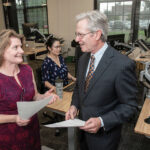 COMMITTED TO COLLABORATION: Mary Johnson, left, program manager for Polaris MEP and the Rhode Island Textile Innovation Network, speaks with Michael Woody, president of Trans-Tex LLC and RITIN, in 2018. In the background is Tanya Dumrongmanee, Polaris program ­consultant. / PBN FILE PHOTO/MICHAEL SALERNO