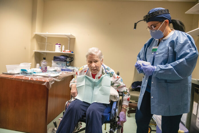 CRUCIAL CHECKUP: Margaret Vargas, right, a dental hygienist with nonprofit CareLink Inc.’s mobile dental clinic, conducts an examination of Sister Anne Kelly at The Villa at Saint Antoine in North Smithfield. The clinic serves 3,000 patients at 53 Rhode Island nursing homes.  / PBN PHOTO/MICHAEL SALERNO