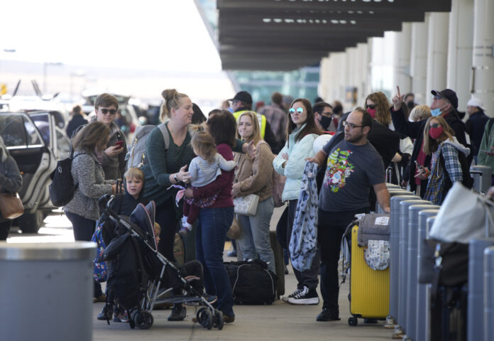 Virus Outbreak Holiday Travel TRAVELERS LINE UP at the Southwest Airlines curbside check-in area at Denver International on Sunday. Airlines canceled hundreds of flights Sunday, citing staffing problems tied to COVID-19 to extend the nation's travel problems beyond Christmas. AP PHOTO/DAVID ZALUBOWSKI