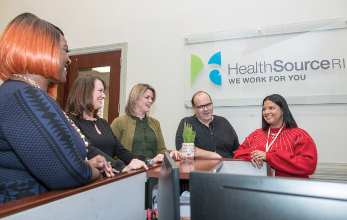 ­COORDINATING COVERAGE: HealthSource RI Director Lindsay Lang, third from left, meets with staff members, from left, Contessa Brown, senior analyst; Leslie Racine Vazquez, operations manager; and Steve Micke and Katherine Rivera in customer service. / PBN PHOTO/MICHAEL SALERNO