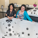 IN STOCK: Carol Benoit, left, owner of Crystal Waters Hot Tubs LLC in Warwick, says she’s selling a lot of hot tubs right now because she’s the only one that has them. At right is Crystal Benoit, finance manager. / PBN PHOTO/MICHAEL SALERNO 