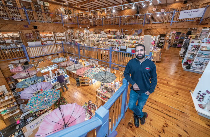 PERFECT FIT: Jay Santiago, who owns the Imagine Gift Store with his wife, Michelle, stands on the upper landing of the second floor of the three-story shop located in the former Lyric Theater building in Warren. Michelle Santiago says the shop, with its quirky items, fun atmosphere and interactive murals, fits seamlessly into the town’s creative energy. / PBN PHOTO/MICHAEL SALERNO