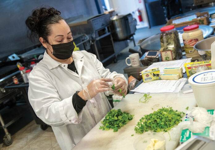 FRESH ­INGREDIENTS: Master chef Rosa Munoz, of Savory Fare, prepares a home-cooked meal in the commercial kitchen at food incubator Hope & Main in ­Warren. / PBN PHOTO/MICHAEL SALERNO
