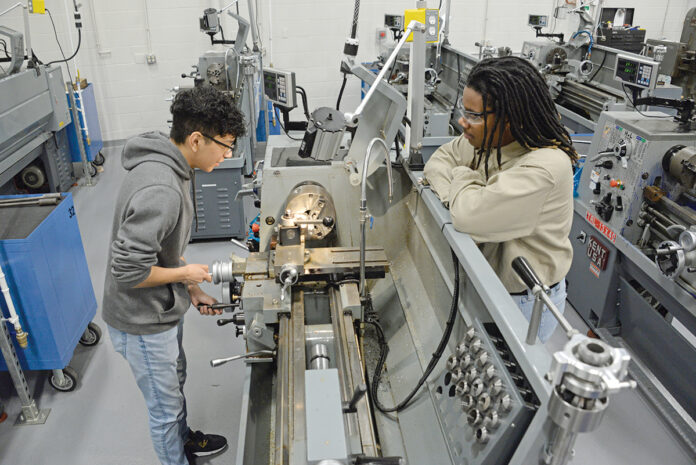 LATHE ­LESSONS: Wilbert Cante, left, and Melvin Shaw, both machine technology students at William M. Davies Jr. Career and Technical High School in Lincoln, work on the manual lathe machine. / PBN PHOTO/ELIZABETH GRAHAM