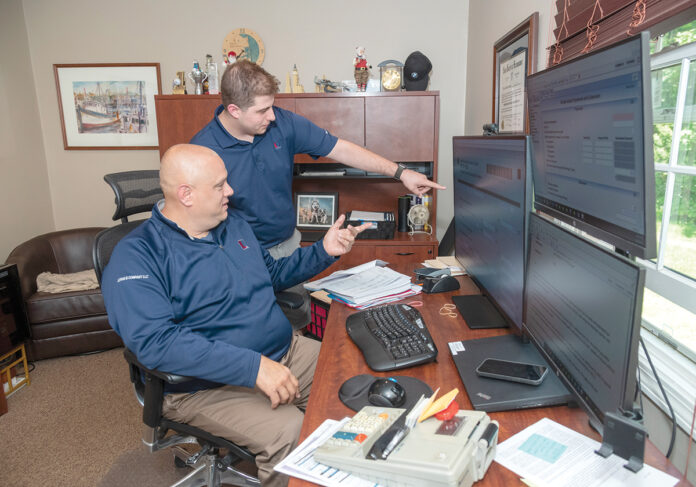 MUTUALLY BENEFICIAL: Certified public accountant Jonathan Ucran, left, has had his son, Joshua Ucran, working for him since he opened his business Ucran & Co. LLC in Smithfield 10 years ago. The arrangement allows Joshua to earn some money while providing his father needed assistance around the office. PBN PHOTO/MICHAEL SALERNO