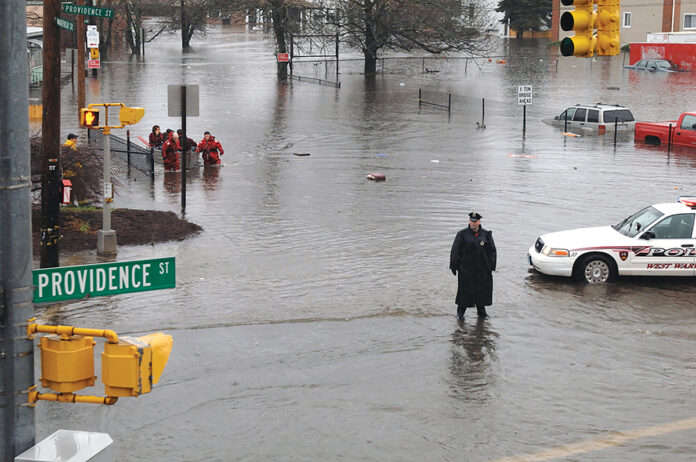 DANGER AHEAD? A police officer directs traffic away from River Street in West Warwick during widespread flooding in April 2010 while firefighters evacuate residents. Following flood insurance rate changes in October, about 10% of homeowners in the state have dropped their coverage.  PBN FILE PHOTO