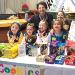 COOKIE SEASON: Janice DiPietro joins a group of Girl Scouts at a cookie booth. COURTESY GIRL SCOUTS OF  SOUTHEASTERN NEW ENGLAND