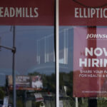A HELP WANTED sign is displayed in a Northbrook, Ill., storefront. The number of Americans applying for unemployment benefits fell last week and remains historically low even as the U.S. economy slows in the midst of decades-high inflation. / AP PHOTO/NAM Y. HUH