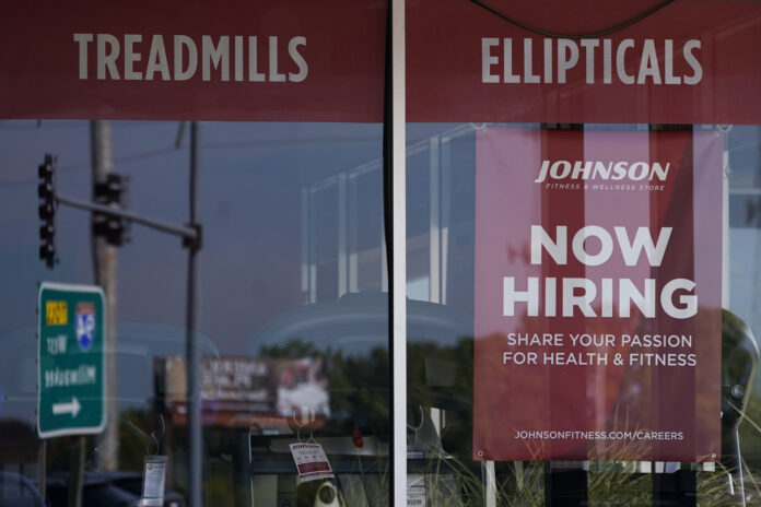 A HELP WANTED sign is displayed in a Northbrook, Ill., storefront. The number of Americans applying for unemployment benefits fell last week and remains historically low even as the U.S. economy slows in the midst of decades-high inflation. / AP PHOTO/NAM Y. HUH