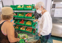 HELPING HAND: Dr. Martin Luther King Jr. Community Center volunteer Susan Barnes, right, assists a customer in the nonprofit organization’s food pantry in Newport. PBN PHOTO/DAVID HANSEN