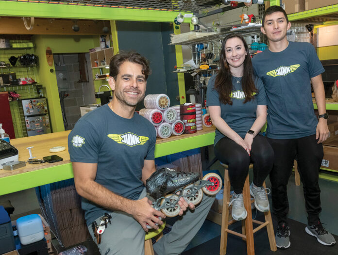 SKATE CREW: Francisco Ramirez, left, is the owner of Junk Wheels, an in-line skate wheel company in Cranston. At right are Kaylyn Fells, who handles the company’s social media, and Edgar Meneses, who works in shipping. PBN PHOTO/MICHAEL SALERNO