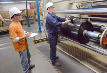 Acquisition allows Trico to expand, add production lines and plastics offered HIGH ROLLER: Greg Viera, left, a machine operator, and Frank Costa, senior machine operator, work on the manufacturing floor at plastics maker Trico Specialty Films Inc. in North Kingstown.
PBN PHOTO/ELIZABETH GRAHAM