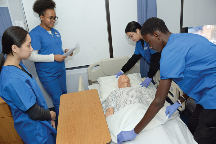 BEDSIDE MANNER: Students, from left, Camille Chiong, Cierra Odiembo, Gianna Sanchez and Djibril Gaye work in a lab at the Rhode Island Nurses Institute Middle College Charter High School in Providence.
PBN PHOTO/ELIZABETH GRAHAM BEDSIDE MANNER: Students, from left, Camille Chiong, Cierra Odiembo, Gianna Sanchez and Djibril Gaye work in a lab at the Rhode Island Nurses Institute Middle College Charter High School in Providence.
PBN PHOTO/ELIZABETH GRAHAM