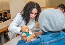 Opening a Pathway: Slate of programs exposing young people of color to field of medicine ON THE MEND: Anna Rezk, a Warren Alpert Medical School student, checks the casting work of a youngster who was assigned to treat a teddy bear with a broken arm at the Black Men in White Coats youth summit at the Brown University medical school in October.
PBN PHOTO/MICHAEL SALERNO
