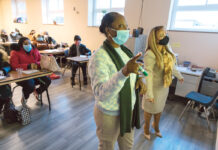 HEAD OF THE CLASS: Teacher Luzleny Cutler, right, and student Lucienda Lapointe review English grammar lessons on a board at the front of a classroom at Dorcas International Institute in Providence recently.  PBN PHOTO/RUPERTY WHITELEY